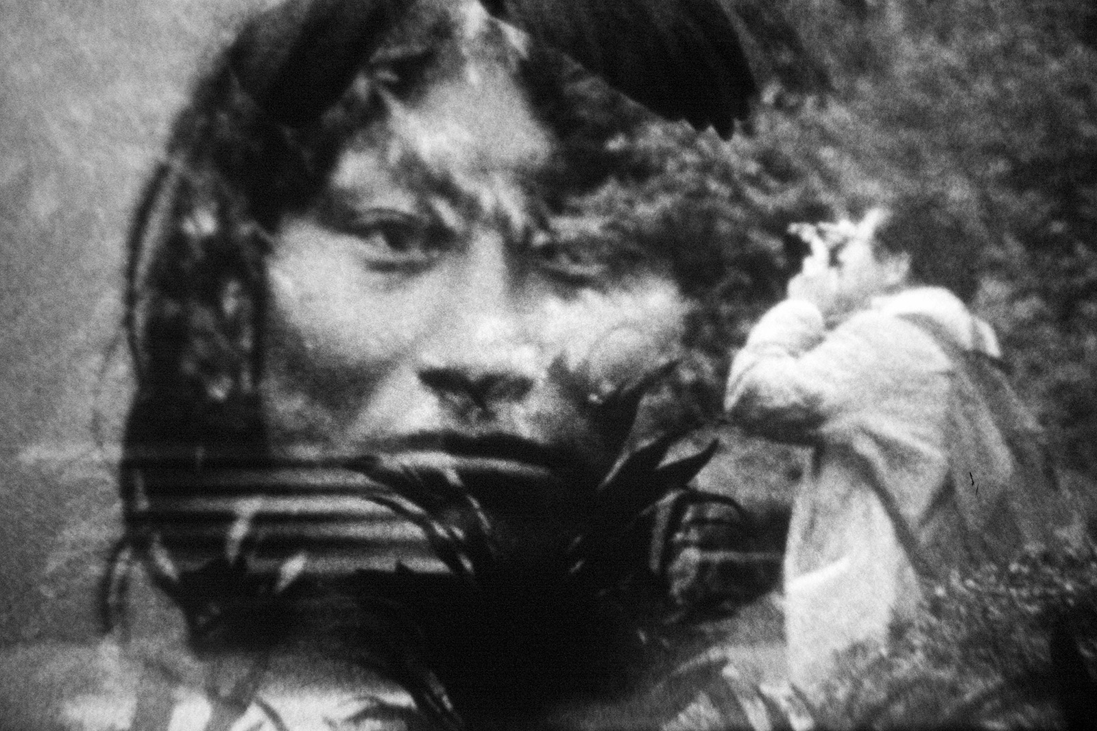 A man photographs a screen showing a head of an indigenous person