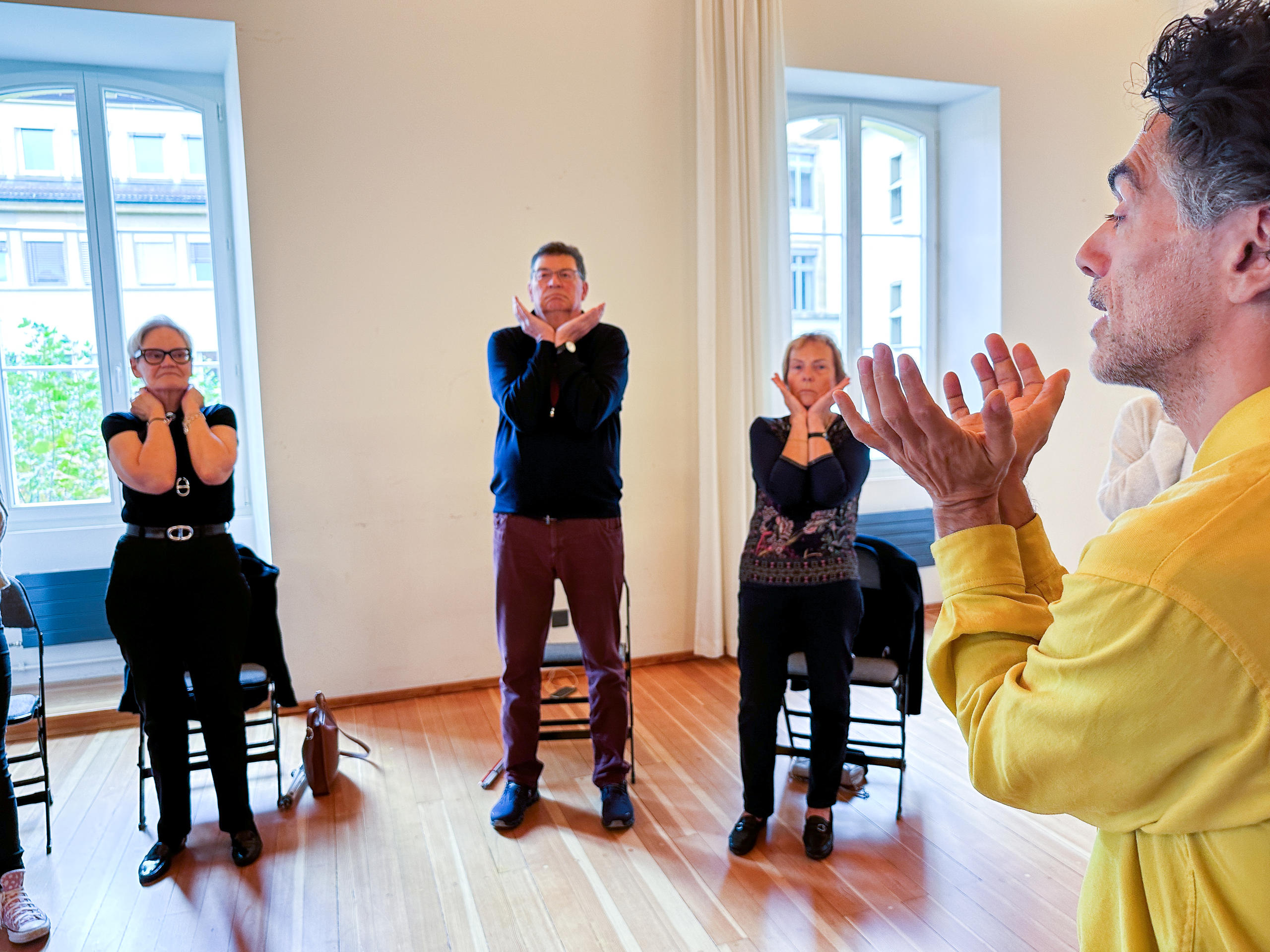 A group of people standing with both hands under their chins around their faces.