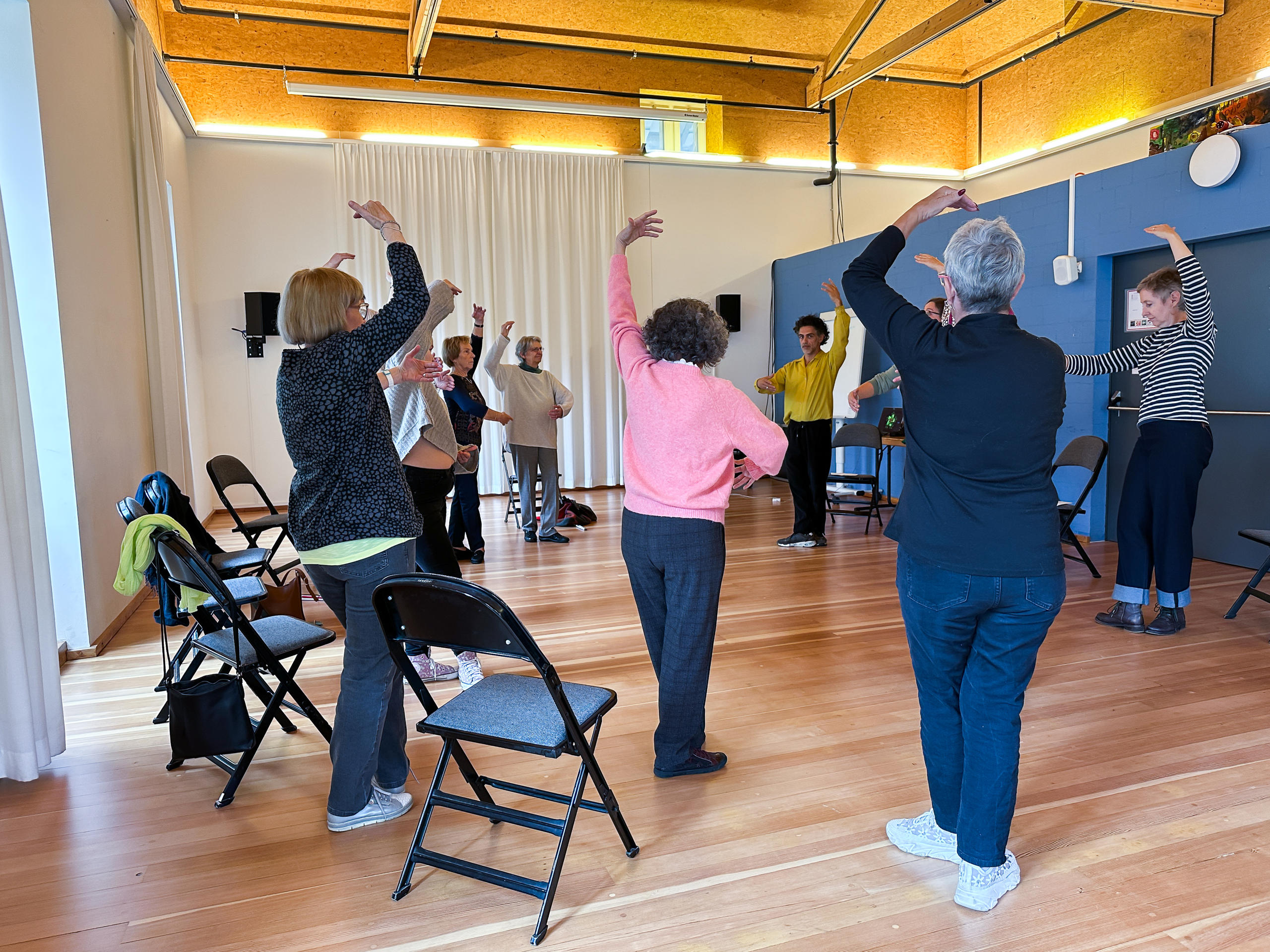 Un groupe de personnes debout mimant des ballerines de danse classique.