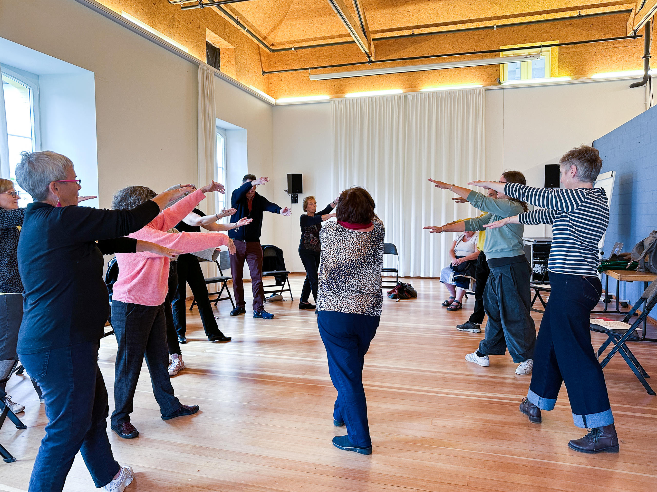 Men and women standing in the room with their arms stretched out.