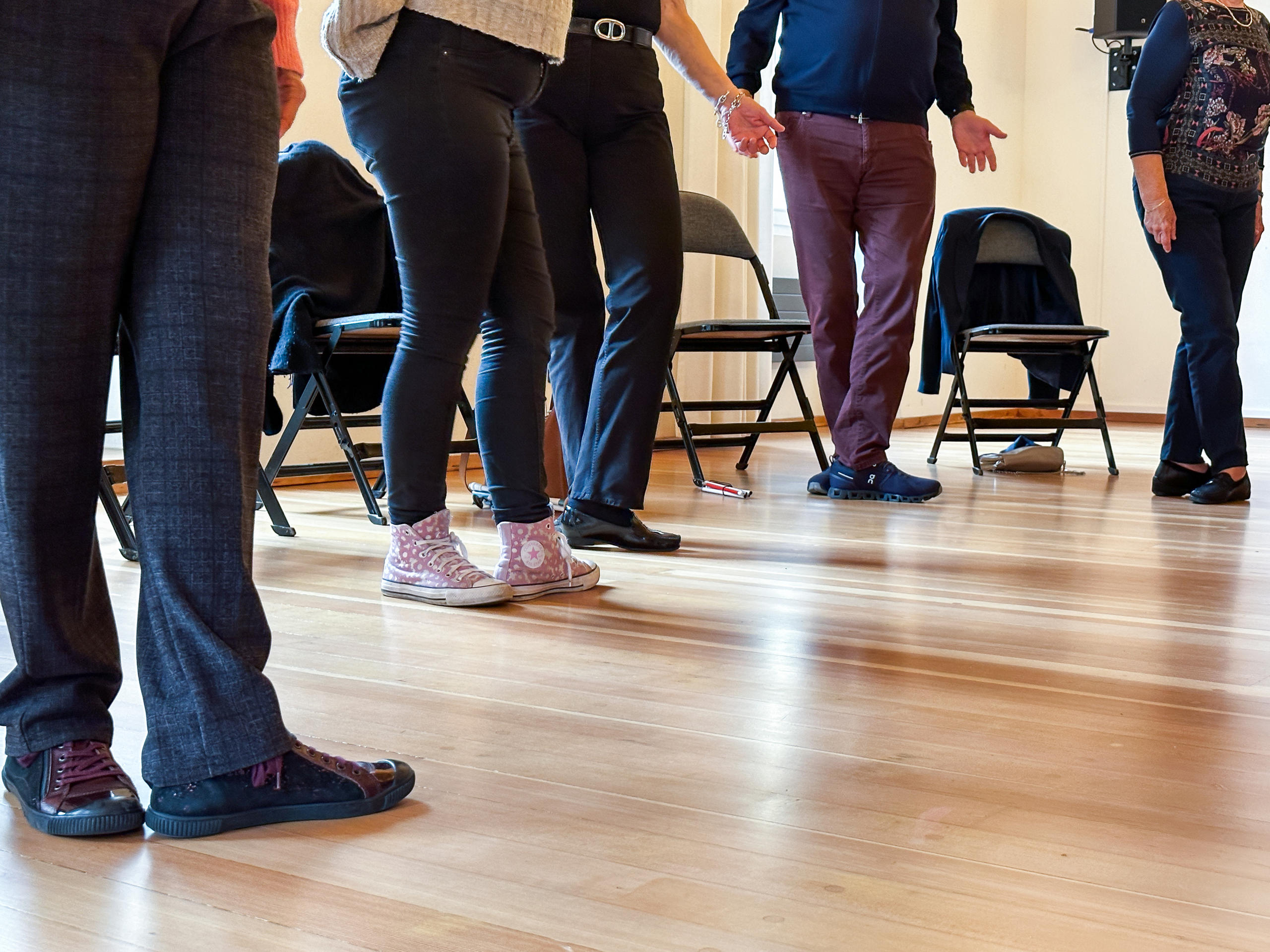 The lower body of the workshop participants, standing in front of their chairs