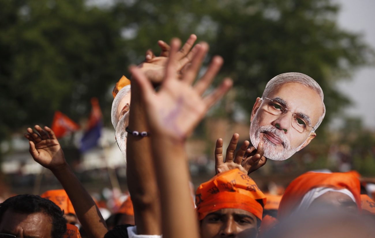 A Bharatiya Janata Party (BJP) supporter holds up a mask of Narendra Modi
