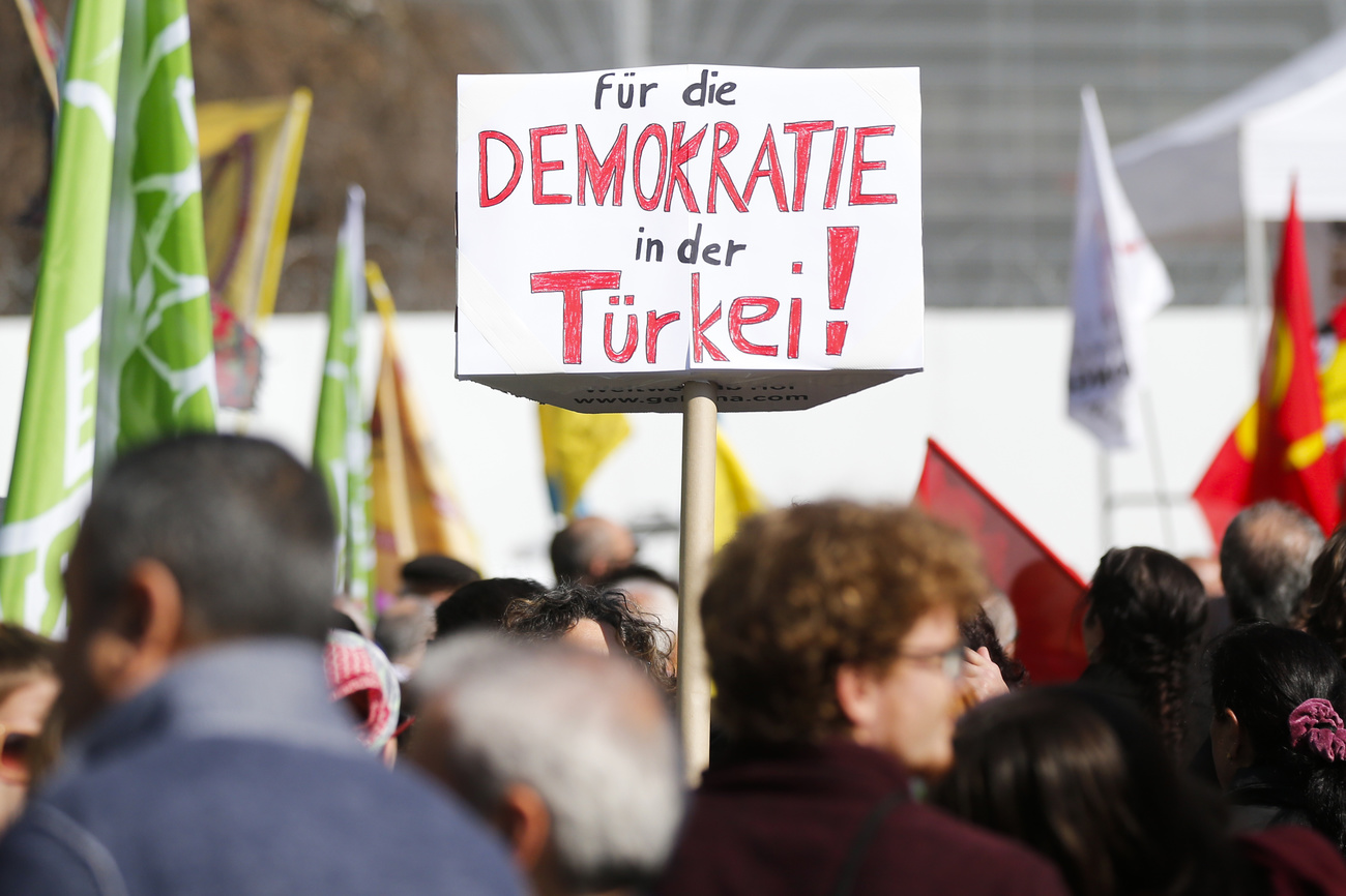 A protest in which one protester holds up a white placard which says ‘Für die Demokratie in der Türkei’, or ‘for democracy in Turkey’, in red and white lettering