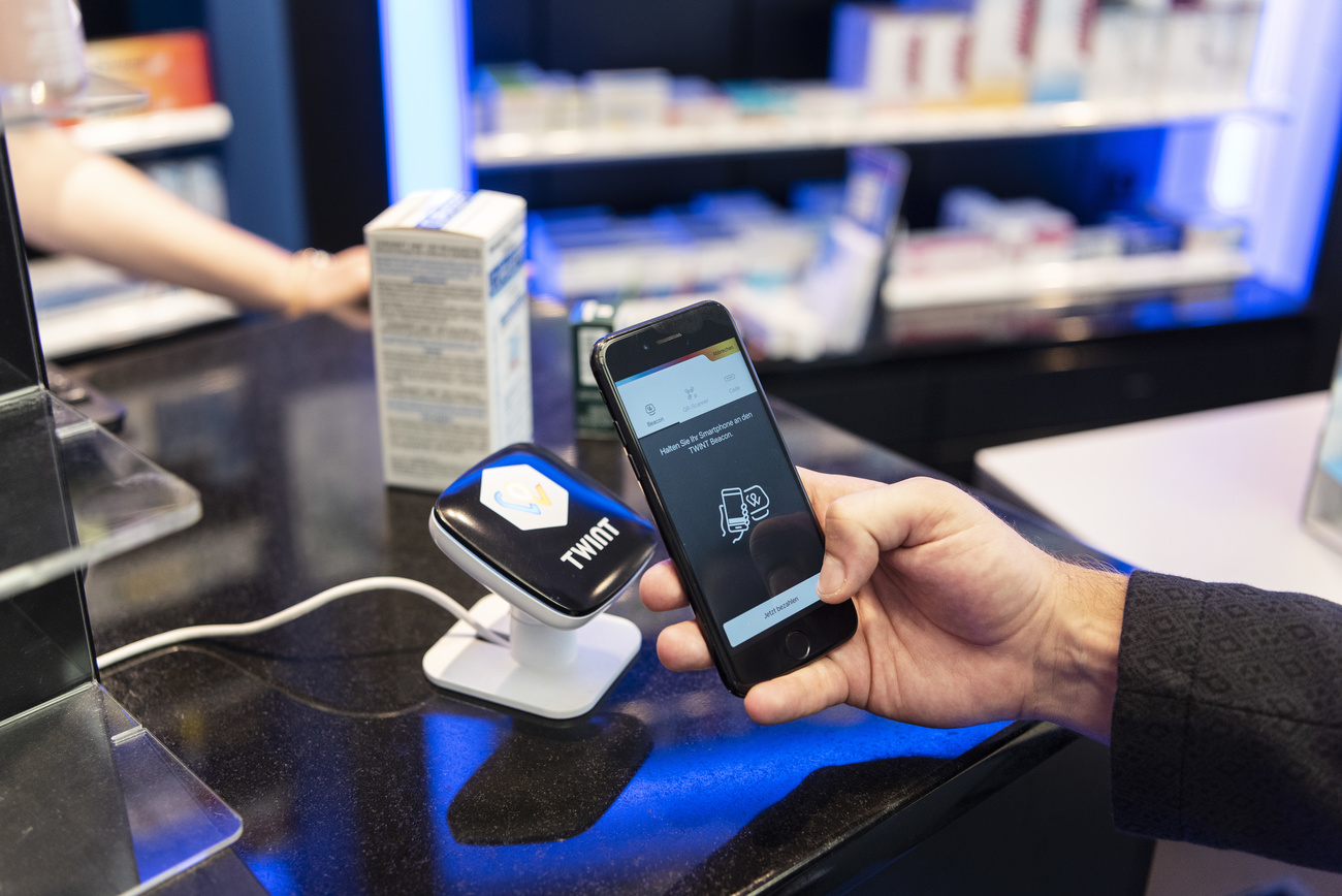 A person uses the Twint cashless payment system via app on a smartphone at a Twint beacon terminal in an Amavita pharmacy in Berne, Switzerland, on May 2, 2018. (KEYSTONE/Christian Beutler)