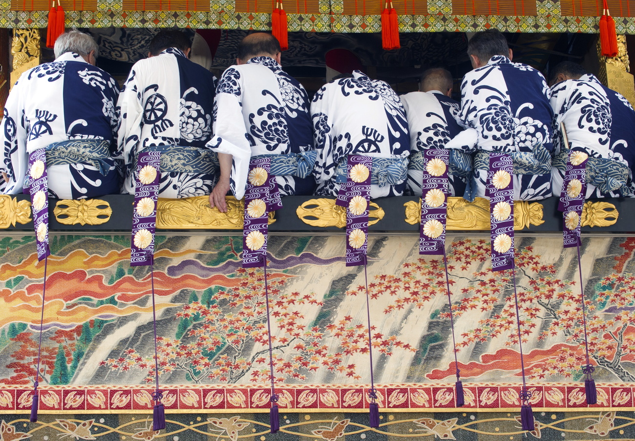 Am Gion Festival in Kyoto sieht man sechs Männer von hinten.