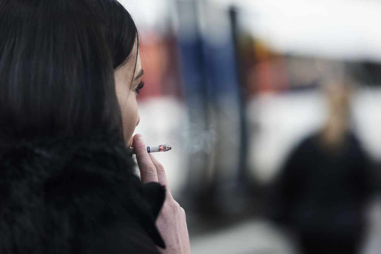 A female smokes a cigarette on a train platform