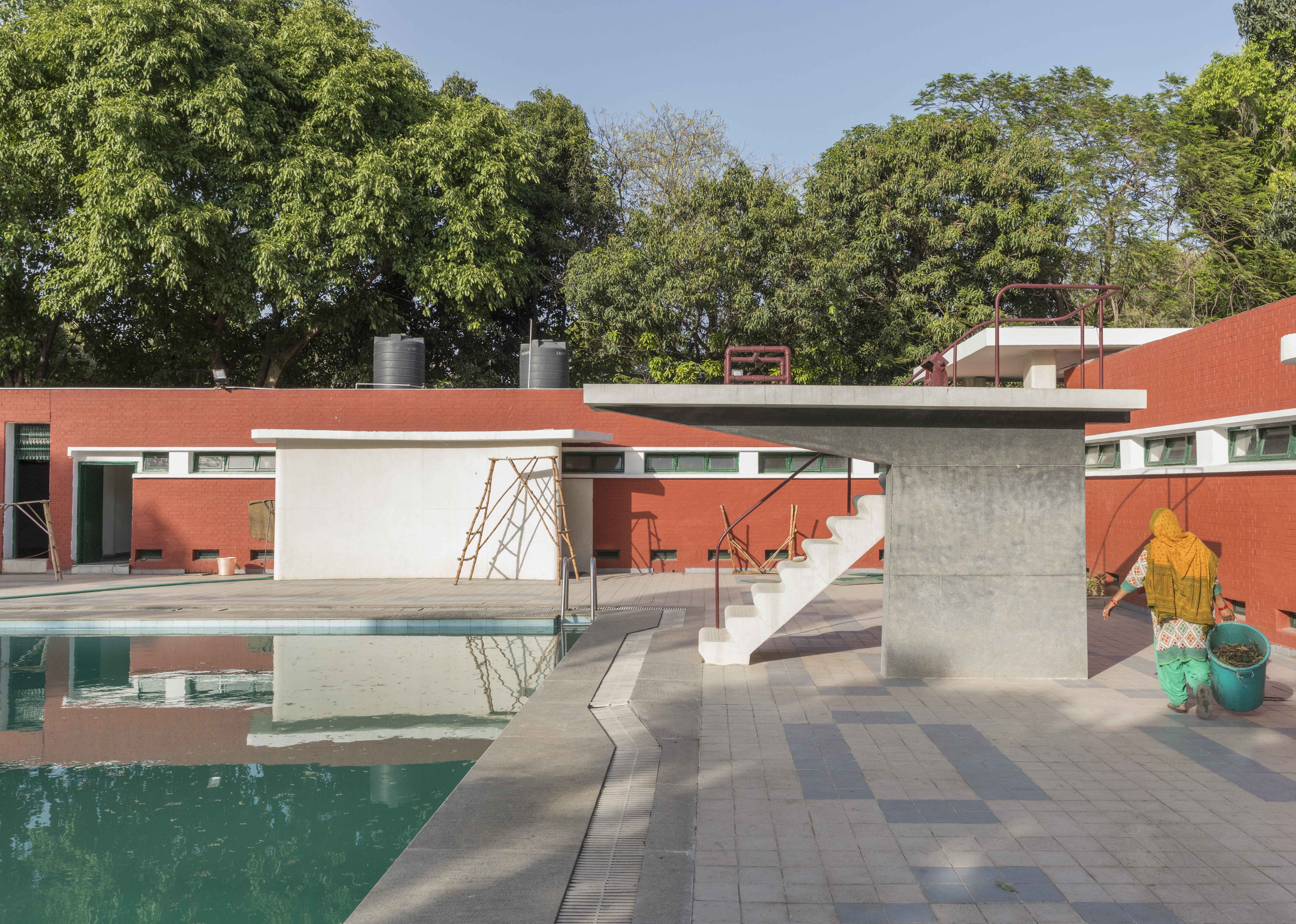 A swimming pool with a diving board made of concrete.