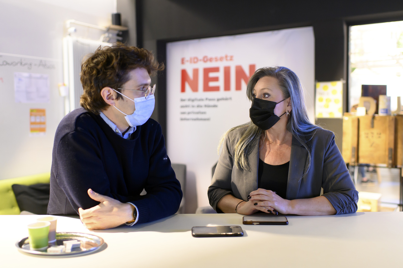 Nuria Gorrite is sitting and speaking with her colleague Roman Felli at the E-ID-Referendums-Komitee. Behind them is a sign that says 'e-ID Gesetz nein'