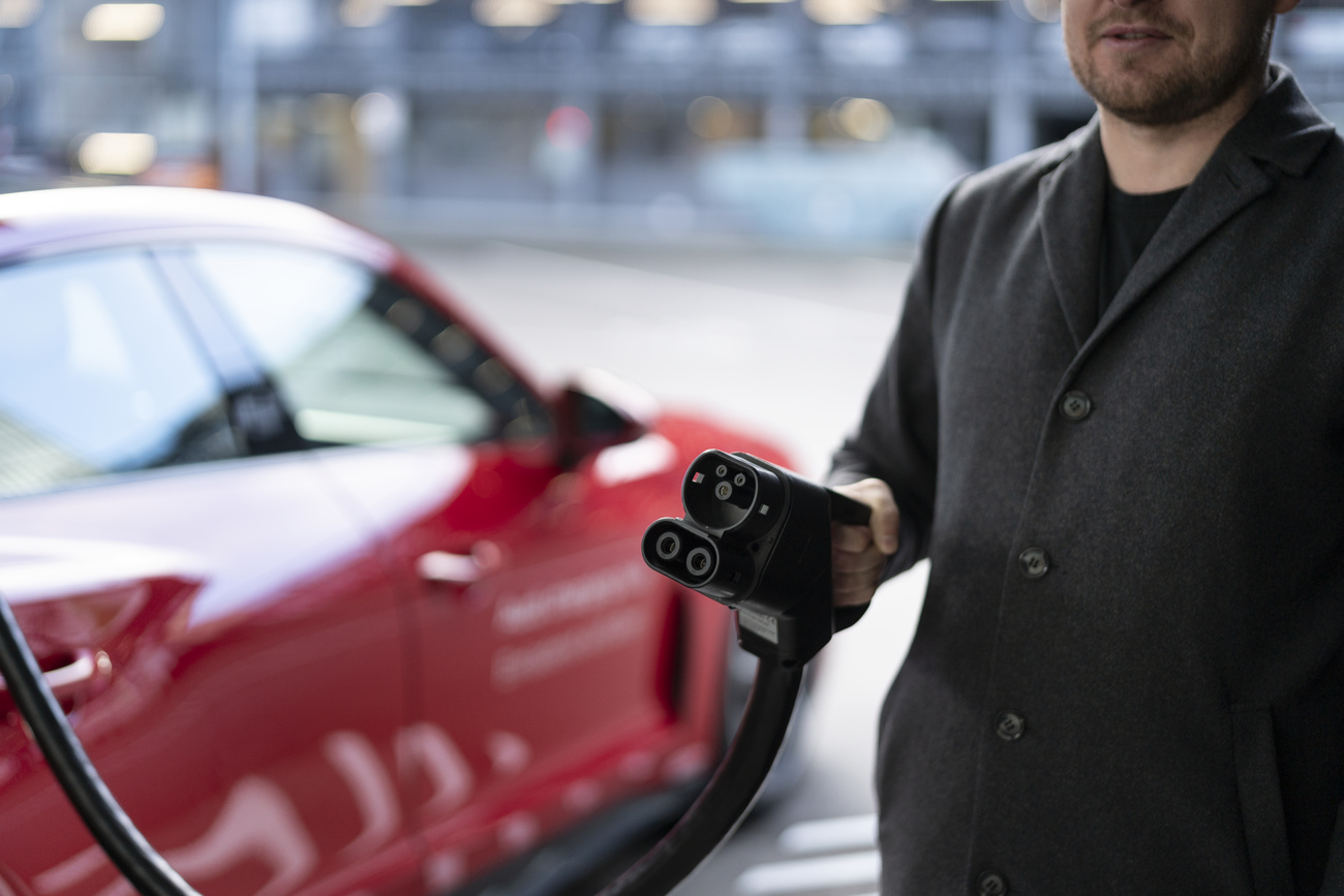 Homme tenant un appareil pour recharger une voiture électrique