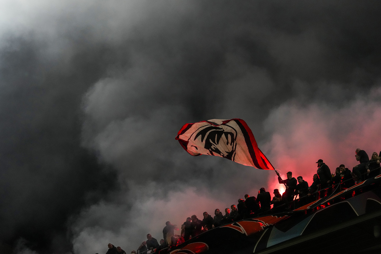 Tifosi fanno sventolare una grossa bandiera del Milan tra i fumogeni.
