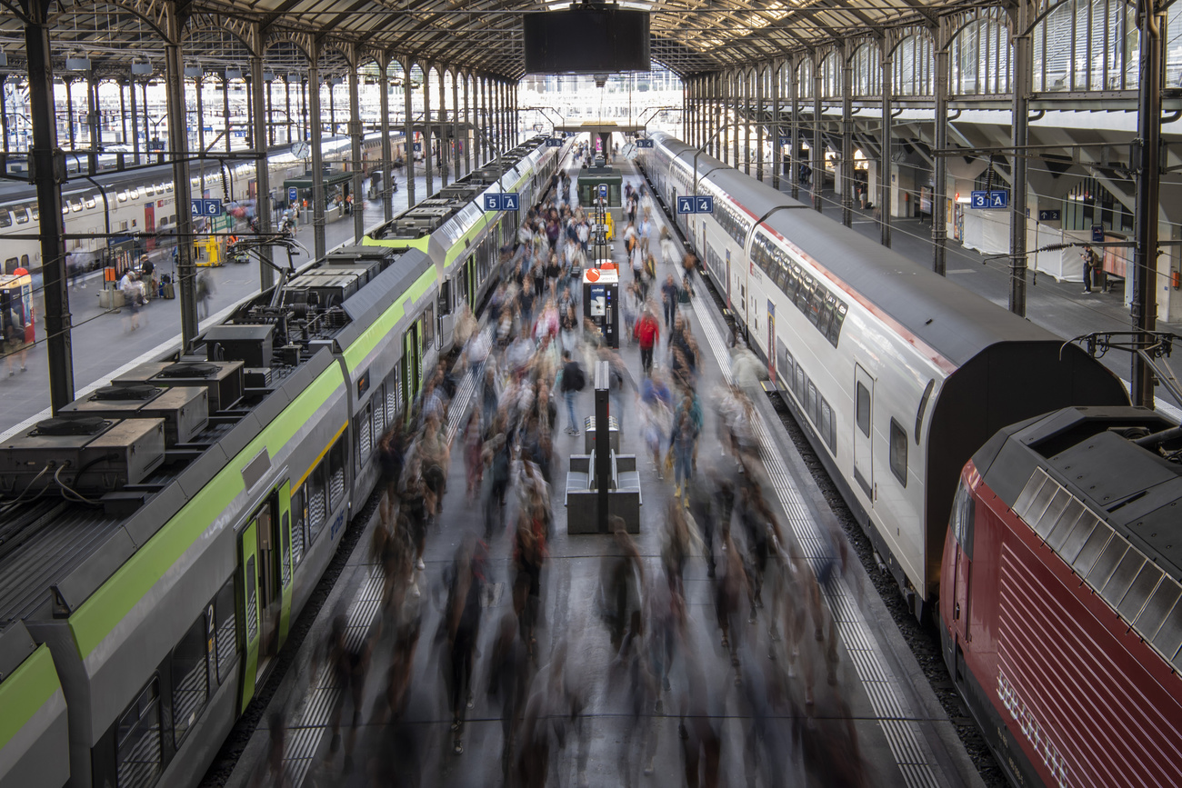 affollata piattaforma tra due binari in una stazione svizzera fotografata dall'alto