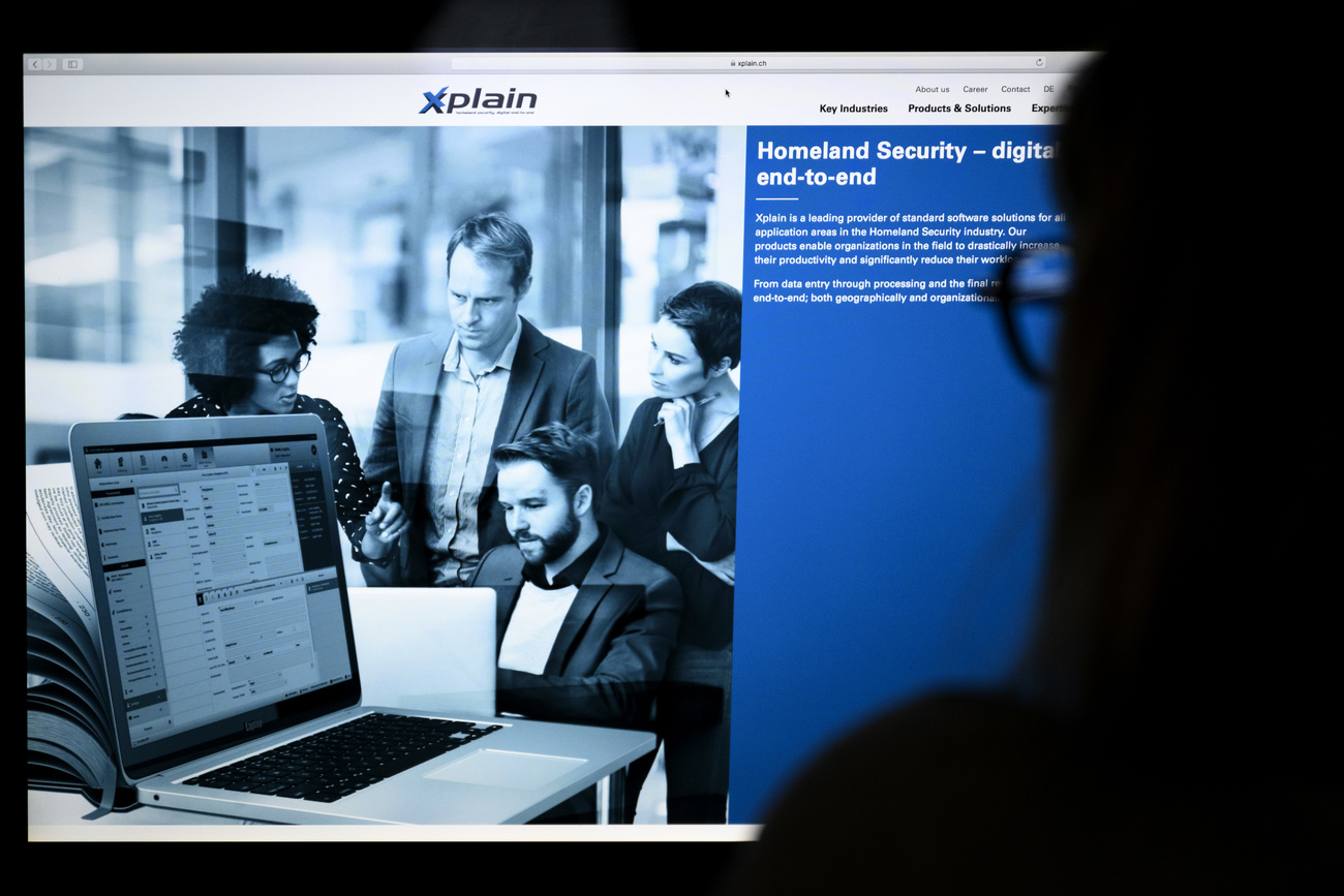 Someone with long hair and glasses, seen from behind, looks at the homepage of the website Xplain