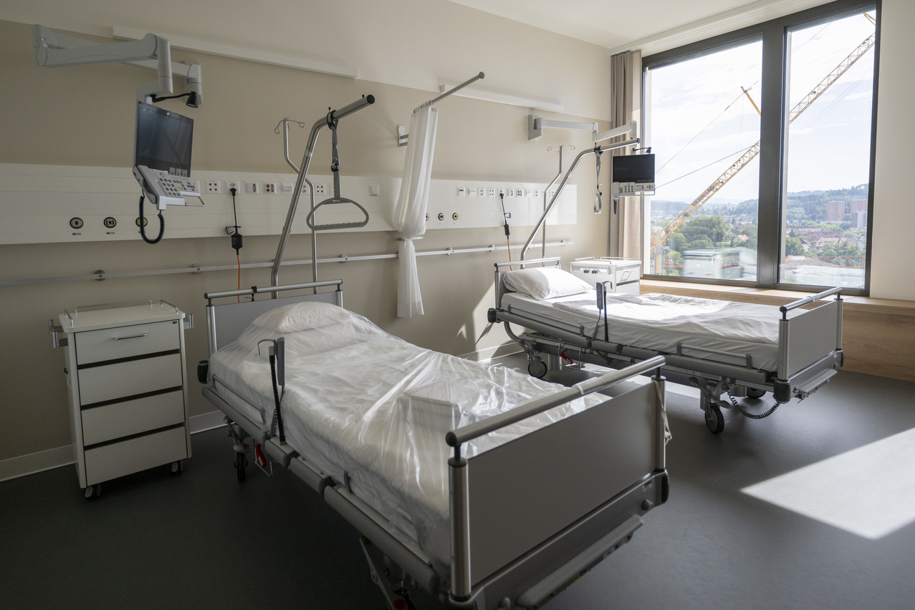 two hospital beds next to eachother. Sun is coming in through the window on the right.