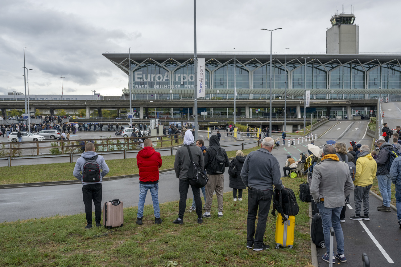 People wait with their luggage in front of the evacuated Euroairport Basel-Mulhouse airport on Friday, October 20, 2023.