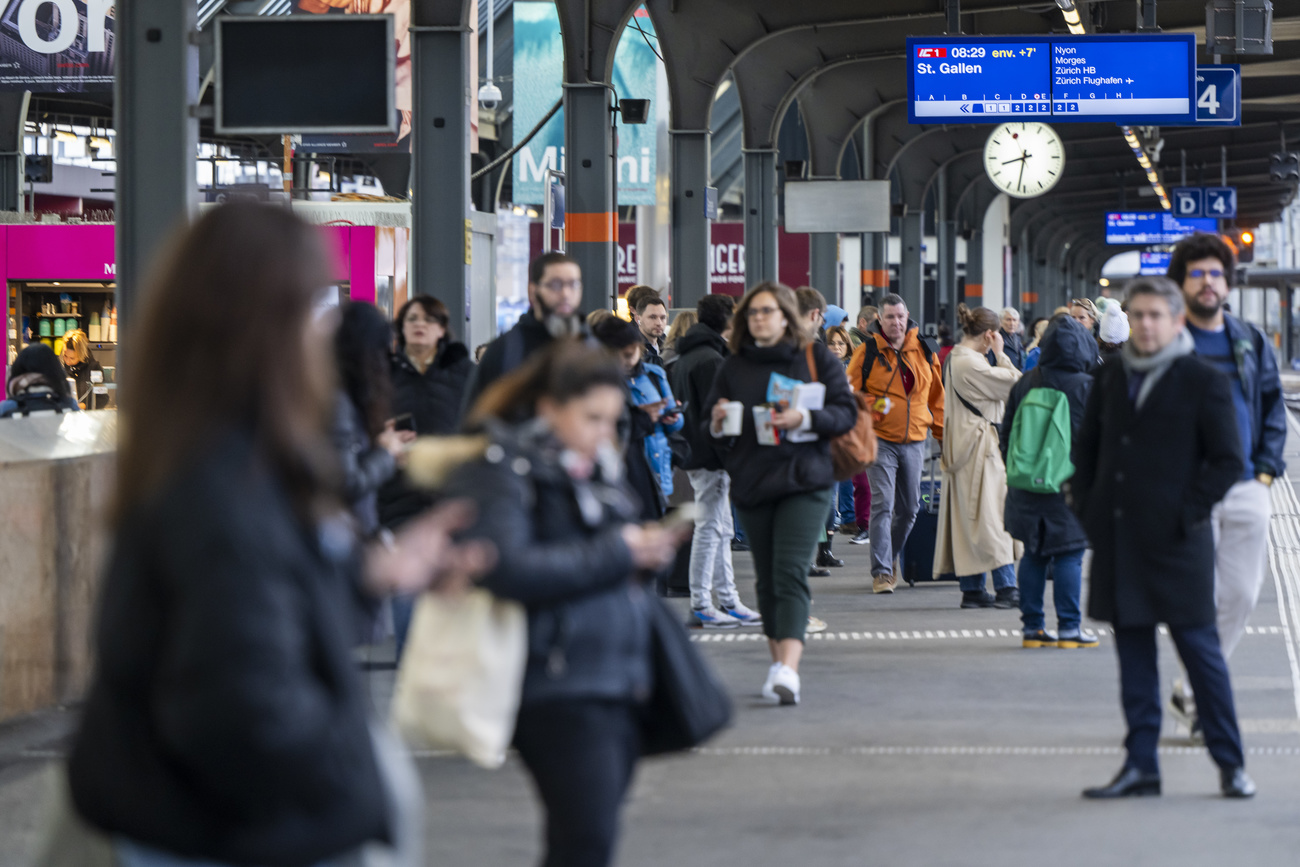 Passengers wait for their train on the platform at Geneva's Cornavin station.