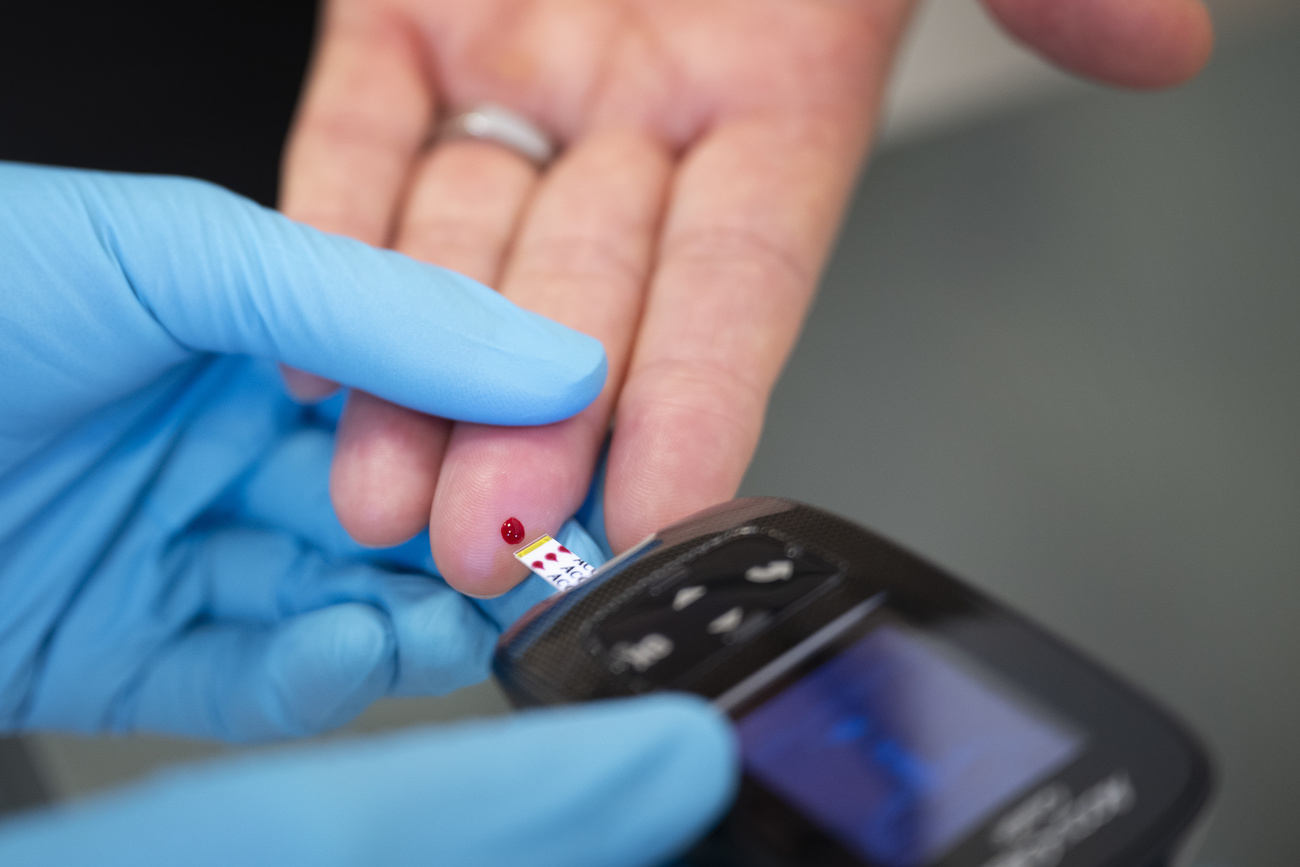 A nurse measures a patient's blood sugar with a glucose meter.