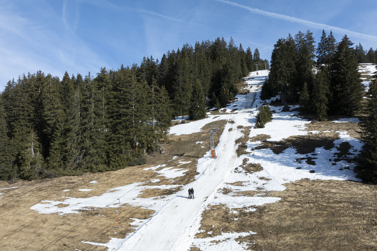 A skier slides down a partially snow-covered ski slope