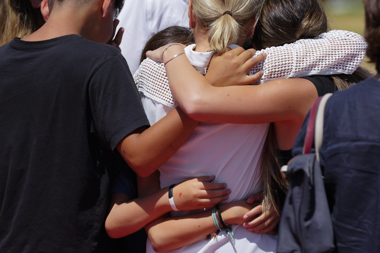a blonde woman wearing a white shirt is hugged by children
