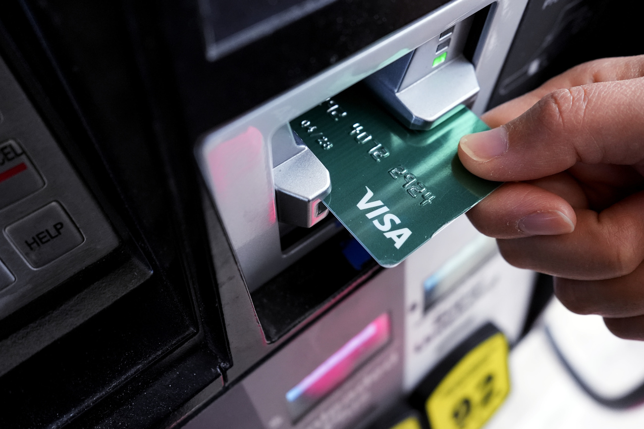 green visa credit card being inserted into ATM
