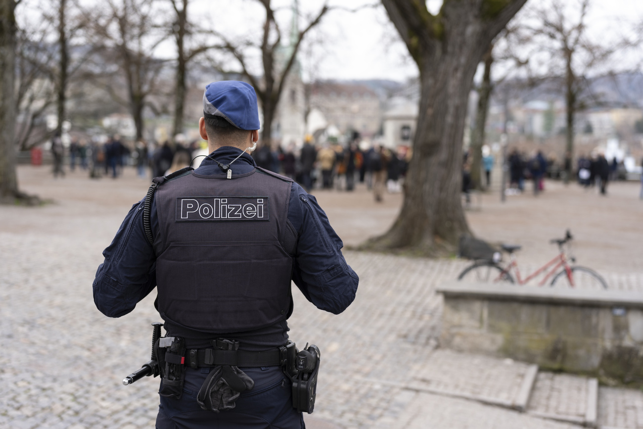 A Zurich city police officer observes the gathering of Jews, Muslims and people of other faiths from a distance, on Sunday 10 March 2024, at Lindenhof square in Zurich to show their solidarity with the victim of the anti-Semitic knife attack by a young Muslim.
