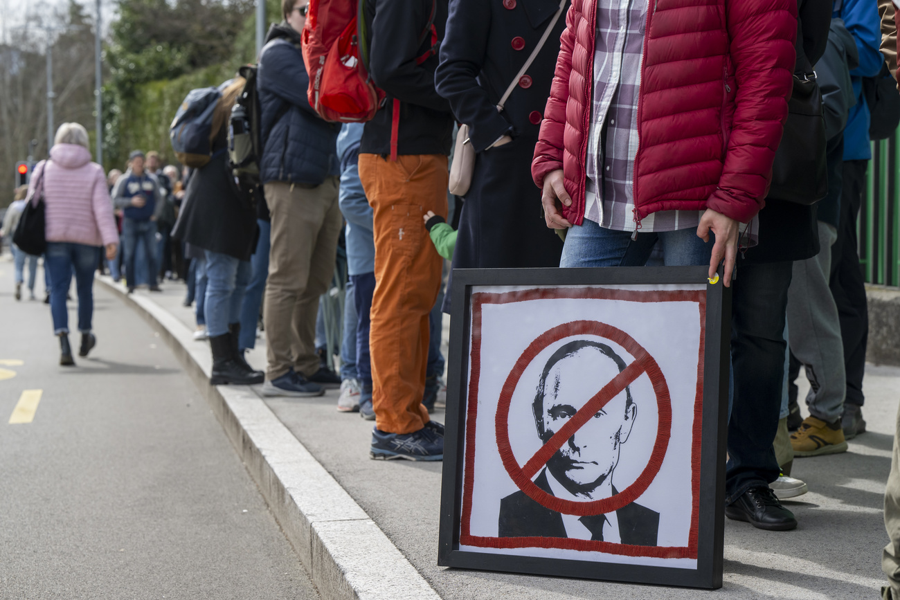 Hundreds of Russian citizens queuing or protesting on the road near the Russian embassy in Bern poster with Putin's head crossed out