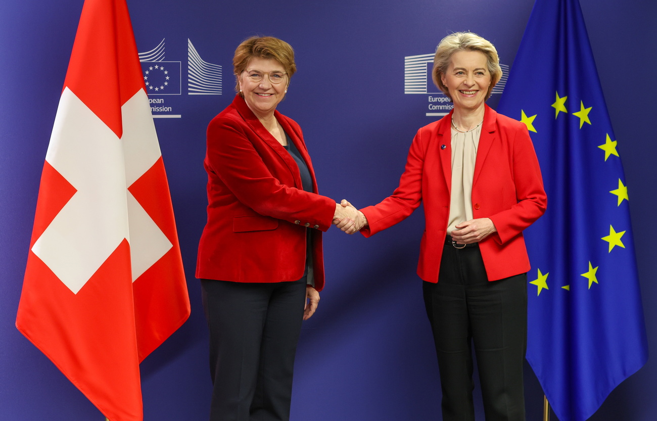 European Commission President Ursula von der Leyen (R) welcomes President of the Swiss Confederation Viola Amherd with handshake. Swiss and EU flags behind.
