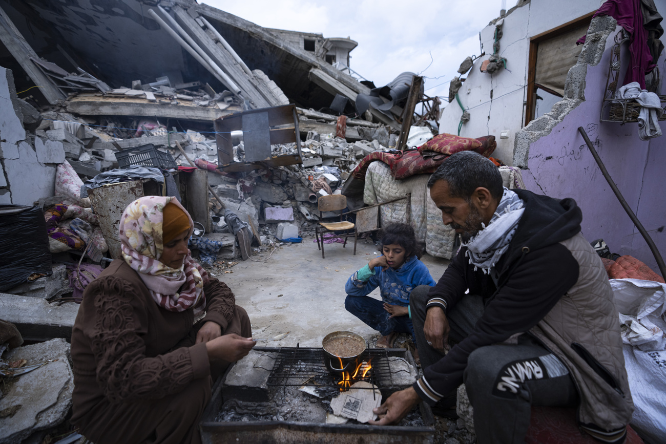 Una famiglia senza casa attorno a un fornello di fortuna a Gaza.