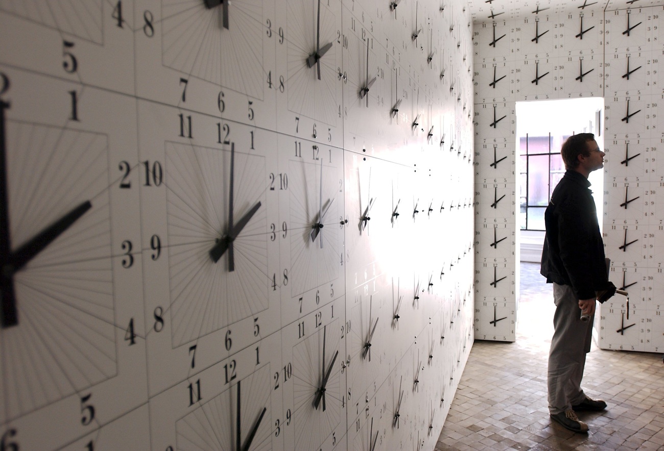 A man looks at a wall of clocks