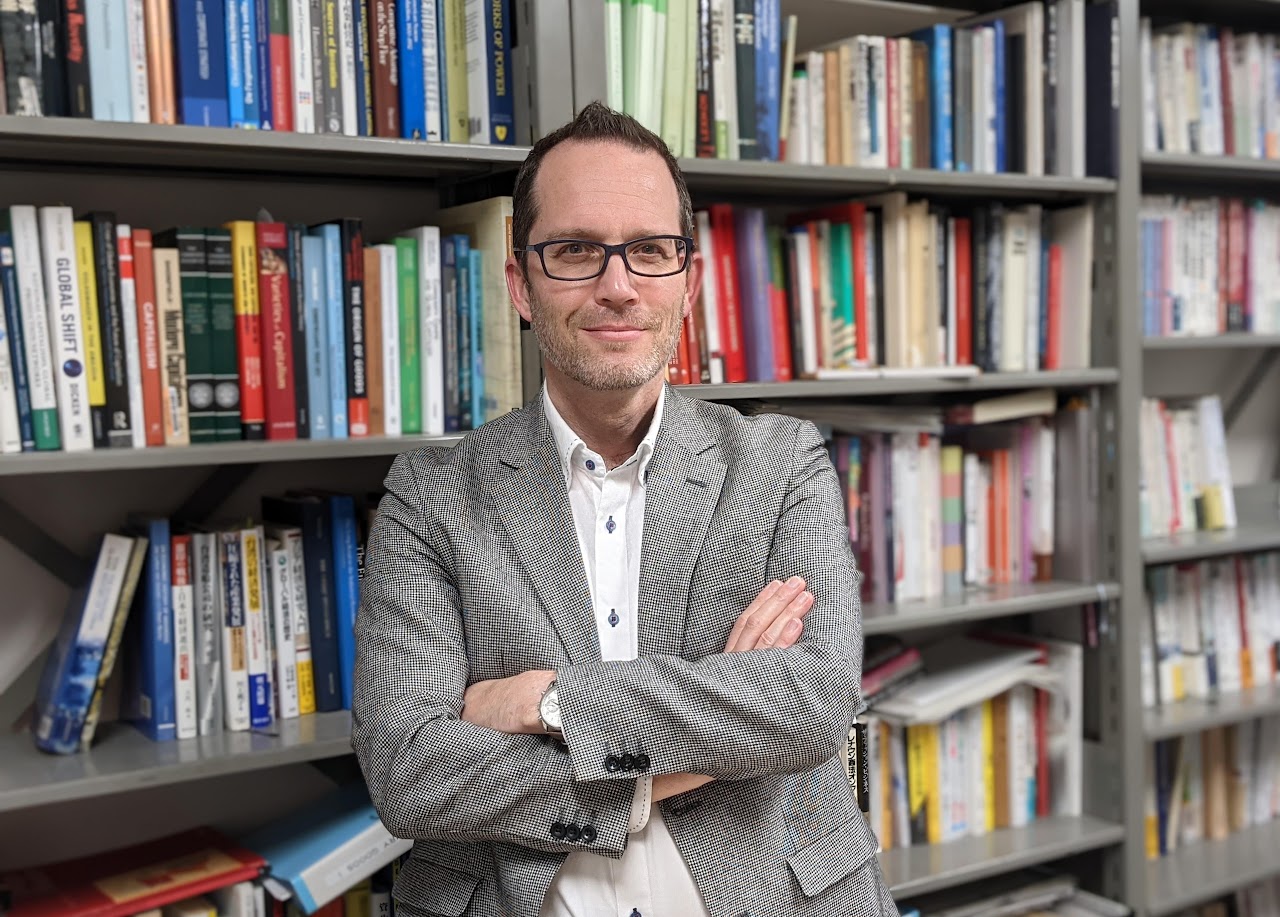 Homme posant devant une bibliothèque