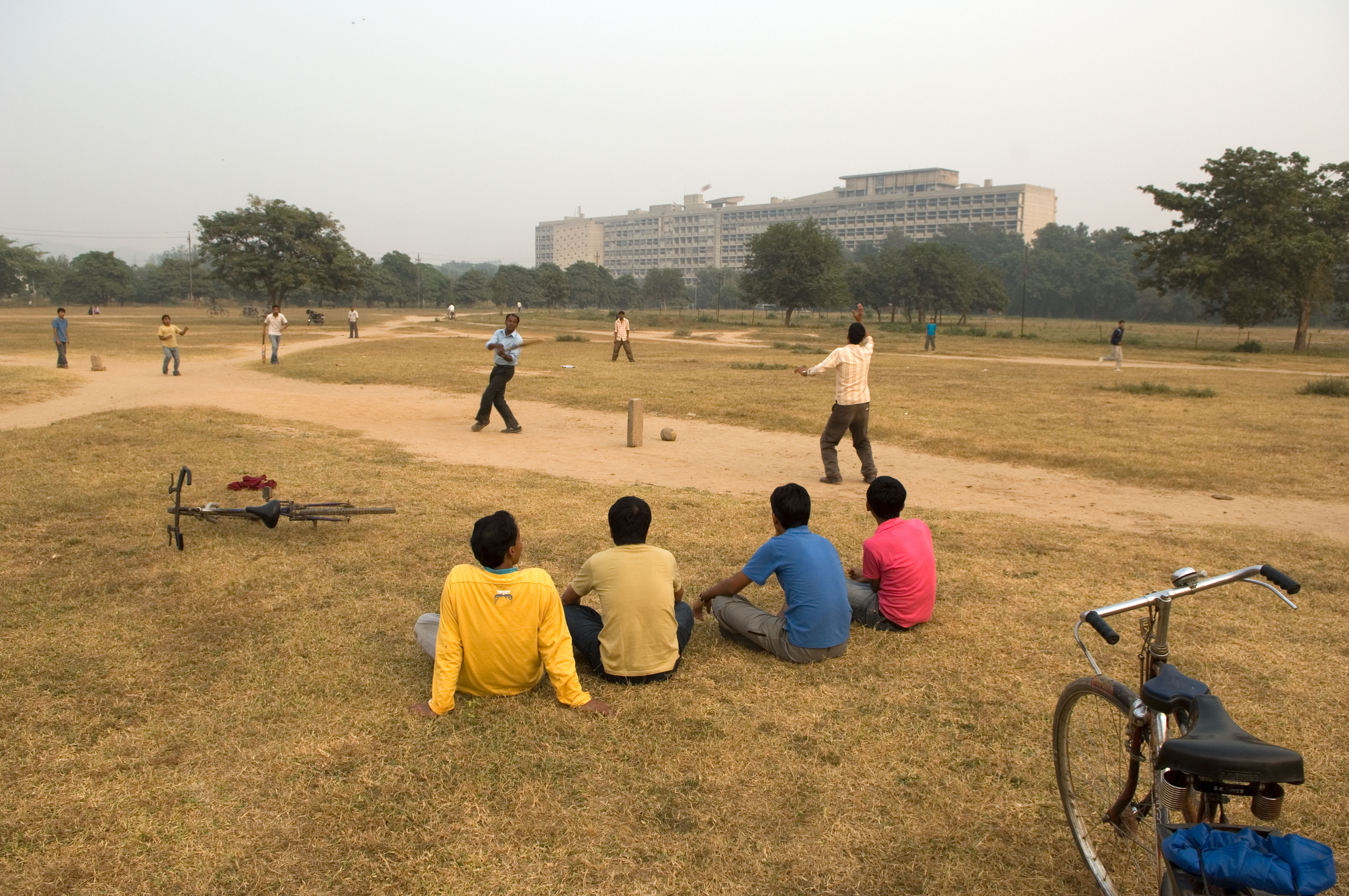 クリケットに興じるインドの人々。バックにはル・コルビュジエ設計のキャピトル・コンプレックス（チャンディーガル）が建つ