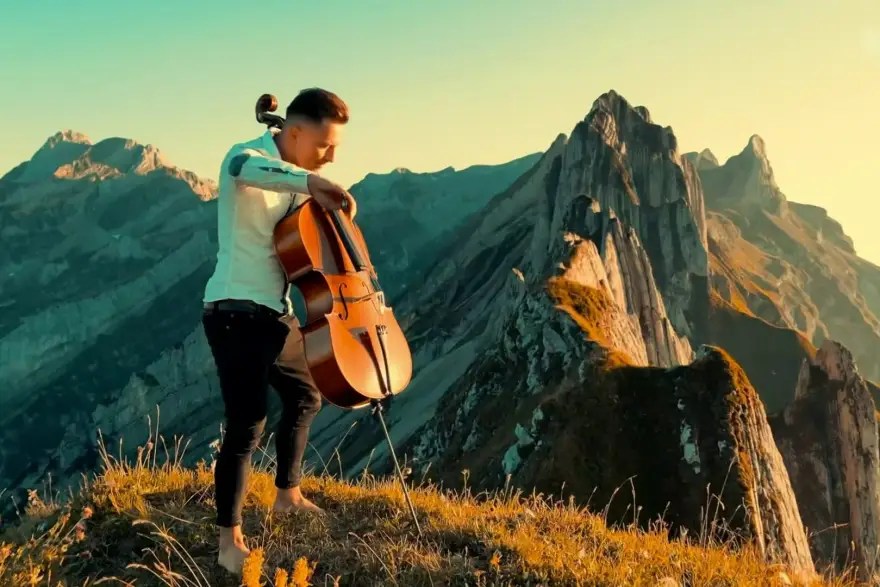 Homme jouant au violoncelle dans un décor de montagnes
