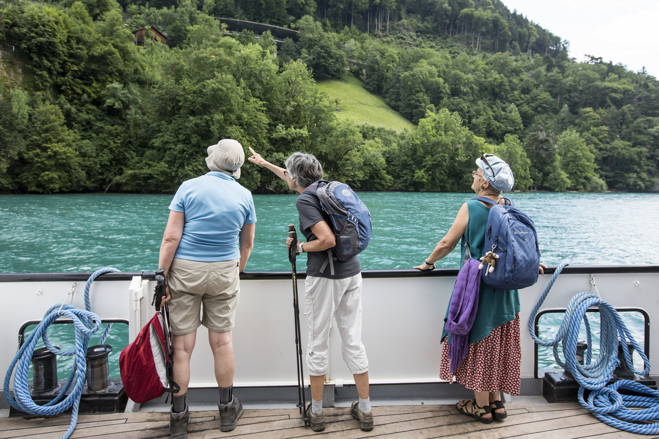 Photo of three people on a boat looking over at landscape