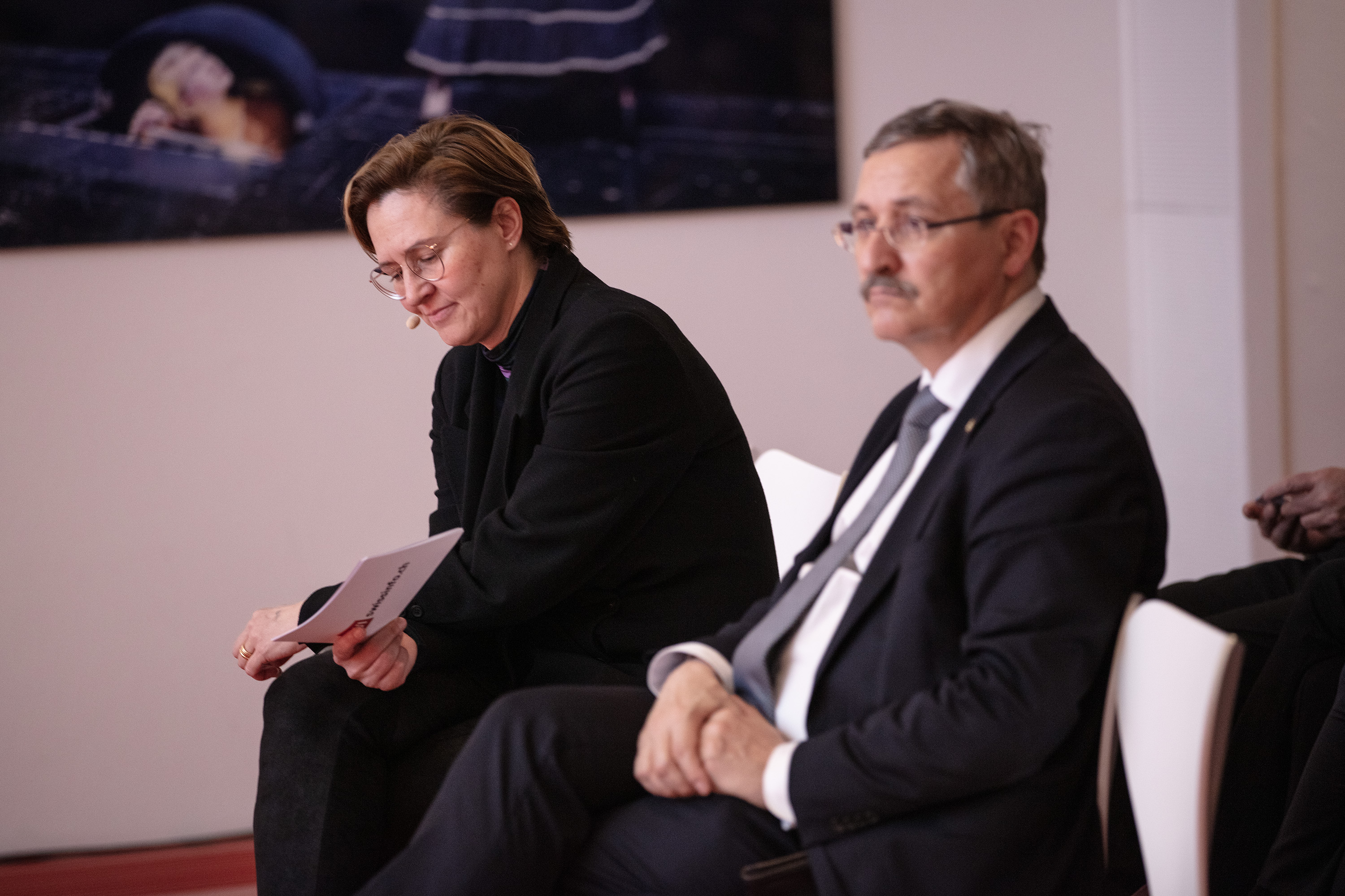 Un homme et une femme assis sur un podium pendant une conférence