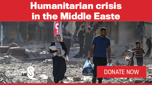 Ein Mann und eine Frau mit einem Kleinkind laufen durch eine zerbombte Strasse.