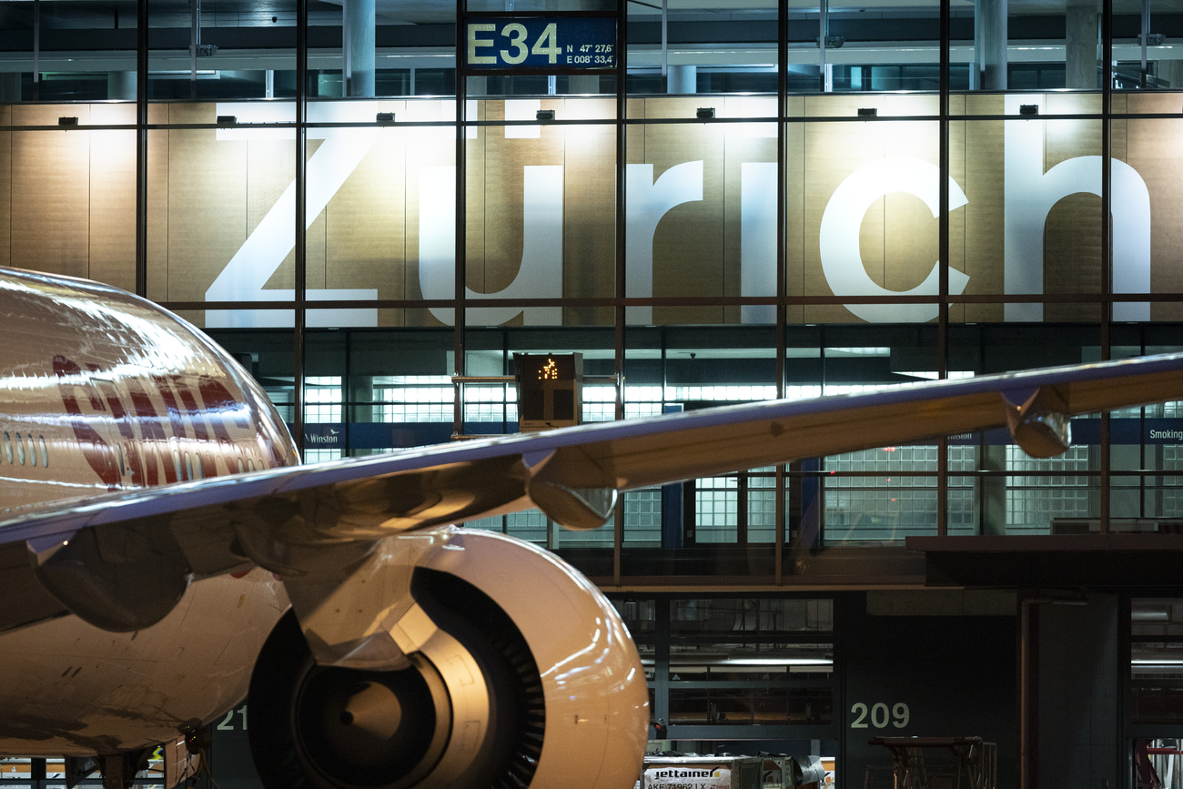 A passenger plane is shown in front of the Zurich airport.