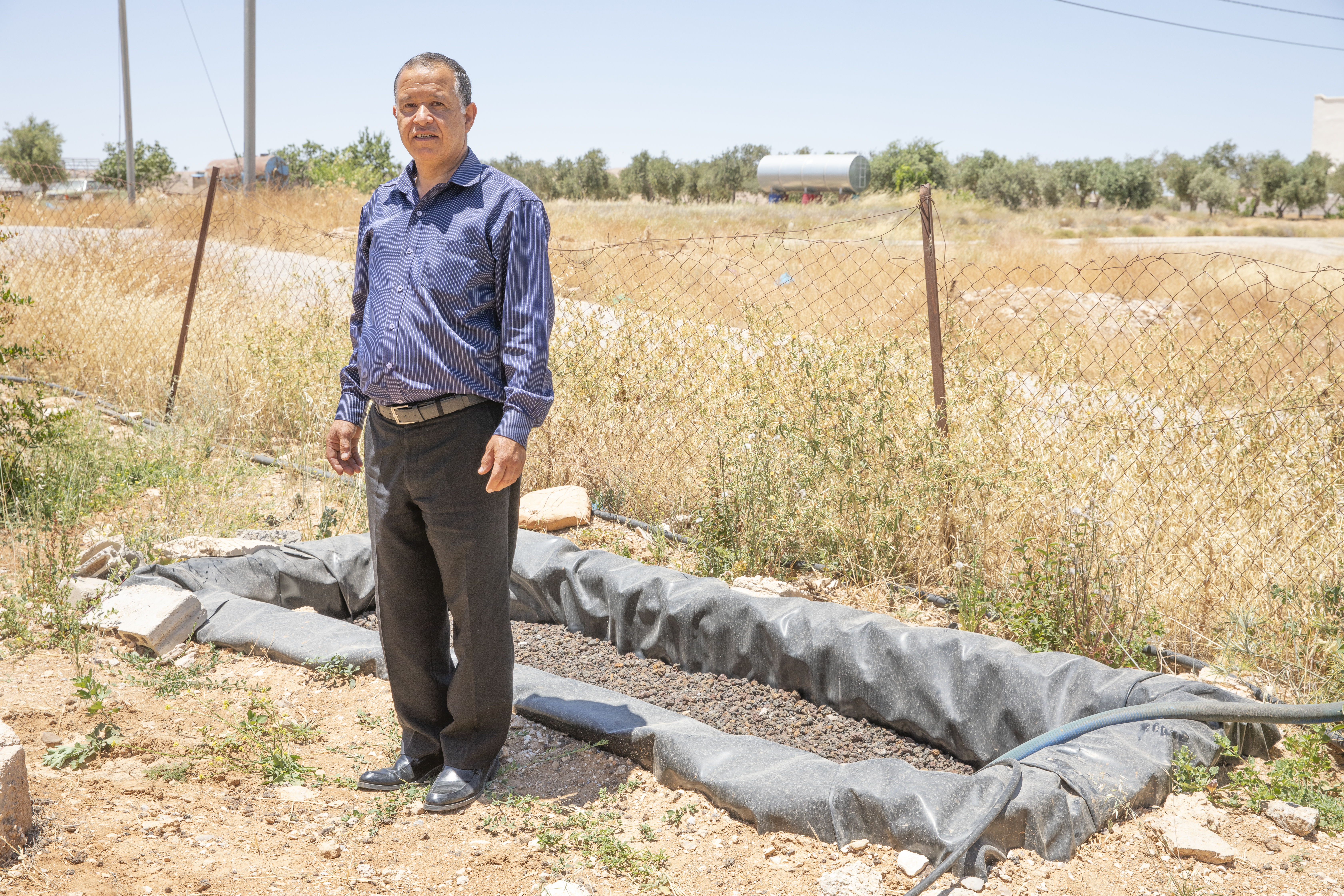 أحد المشاركين في برنامج ميرسي كوربس أحمد الحباحبة (54 عامًا) بجوار نظام تنقية مياه الصرف في منزله.
