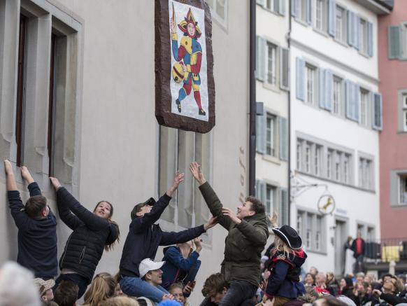 giovani cercano di impossessarsi di un pezzo di panpepato gigante appeso a un tetto