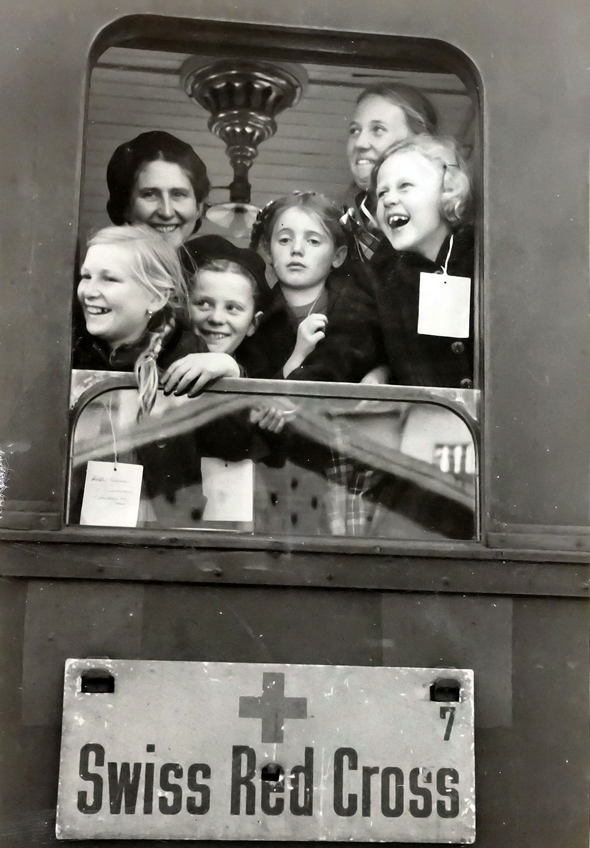 Enfants souriants à la fenêtre d'un train de la Croix-Rouge Suisse