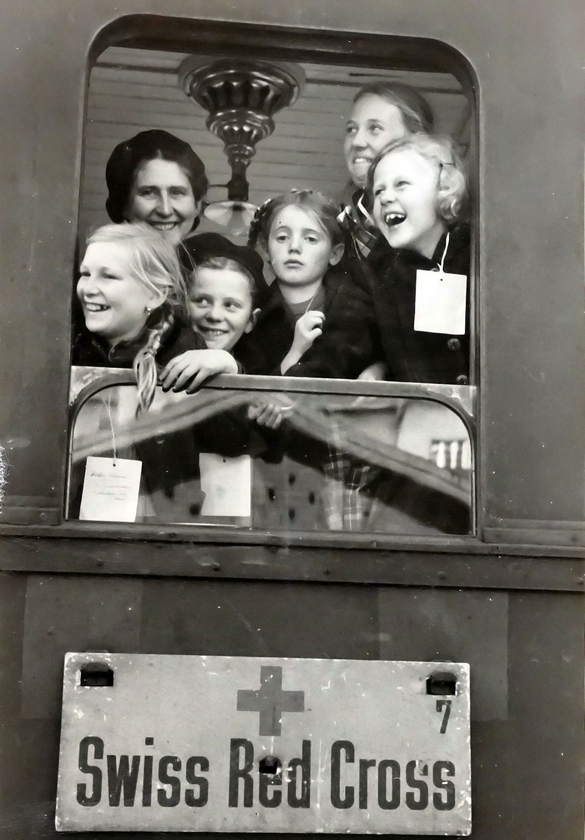 Enfants souriants à la fenêtre d'un train de la Croix-Rouge Suisse
