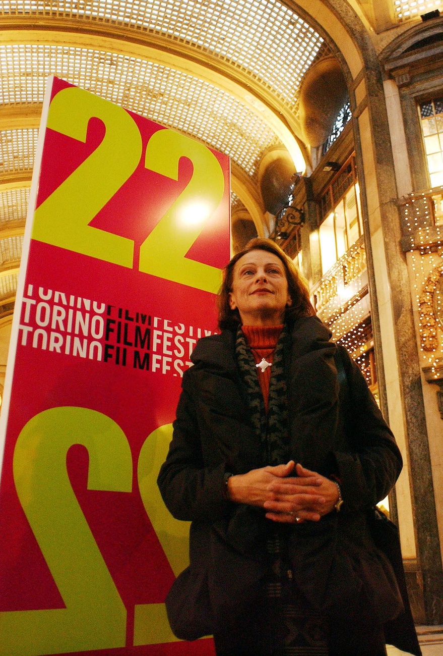 A film director standing in front of an advertising poster at night.