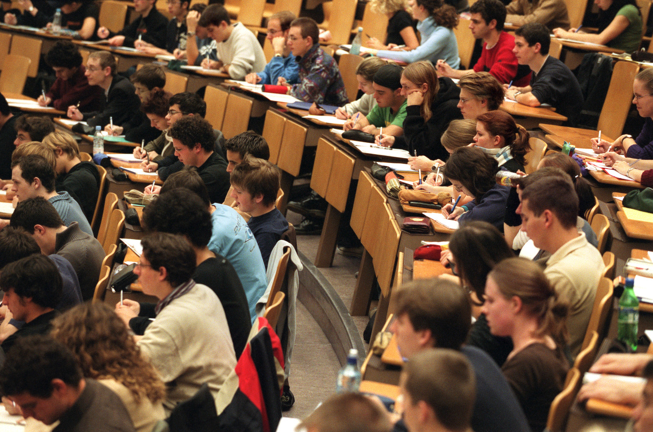 Students sit at wooden desks in a lecture theatre