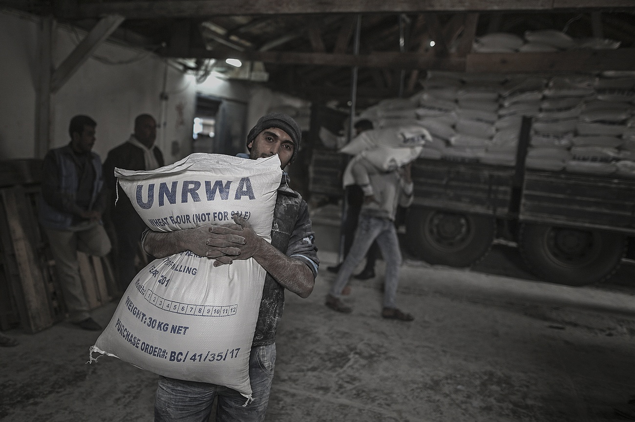 Ein palästinensischer Flüchtling trägt einen Sack mit Mehl mit Aufschrift UNRWA