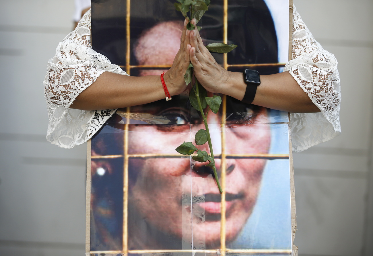 donna tiene mani in preghiera davanti a immagine di Aung San Suu Kyi