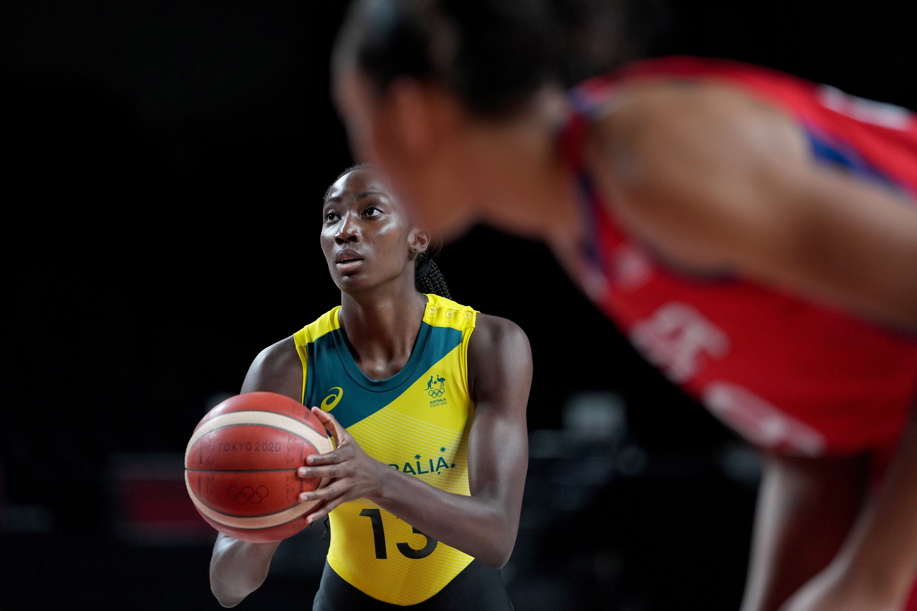 A woman holding a basketball prepares to take a free throw while another player from the other team is seen in the foreground