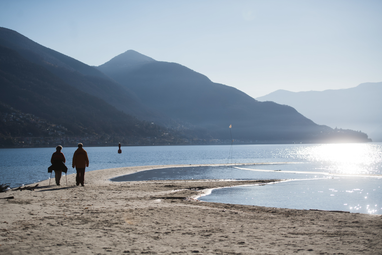 Due persone camminano sulle rive del Lago Maggiore.