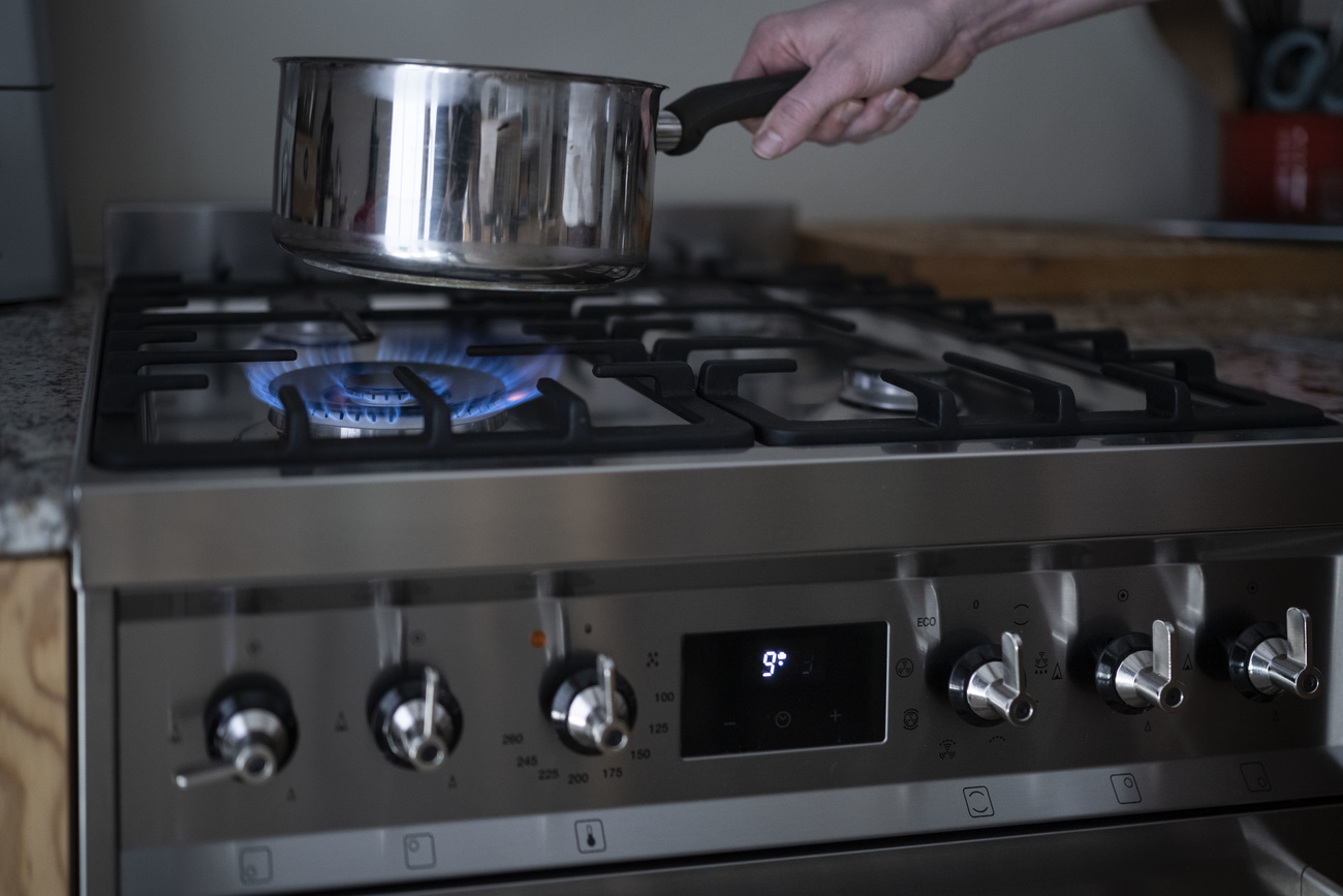 Picture of a person's hand putting a pot on a gas stove