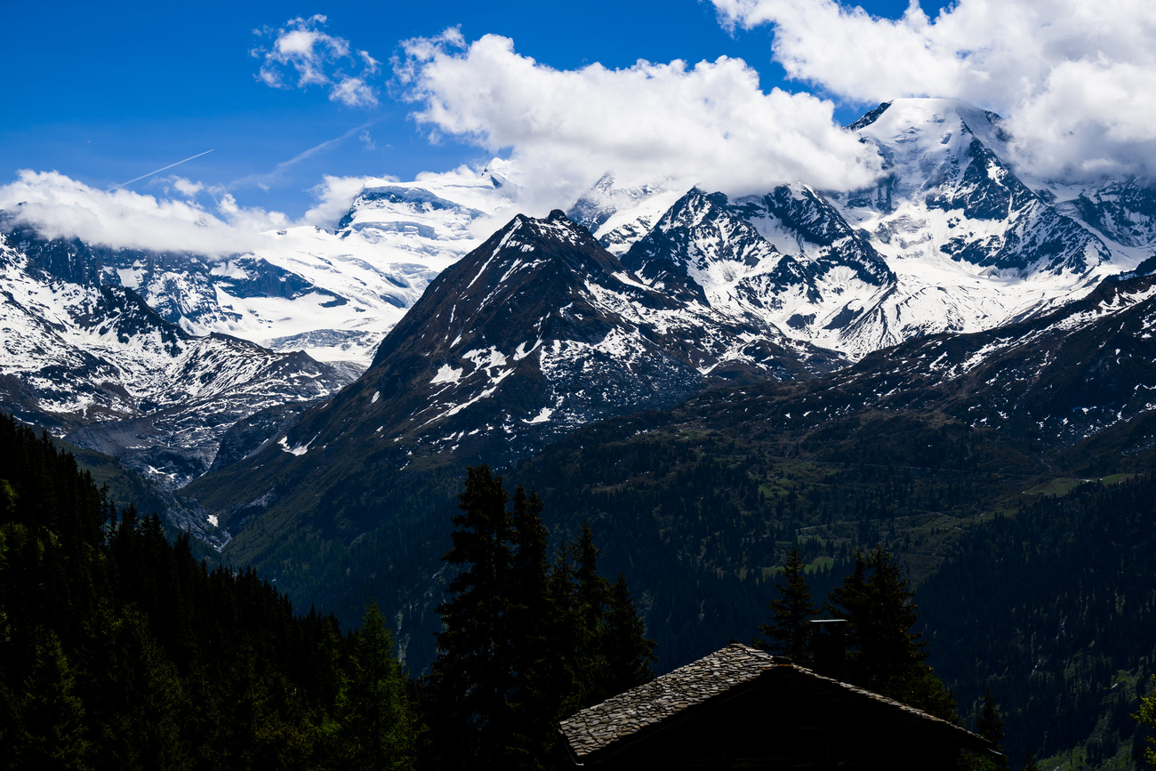 The dramatic, snow-covered mountainscape of the Grand Combin and Petit Combin, with clouds being blown over the peaks
