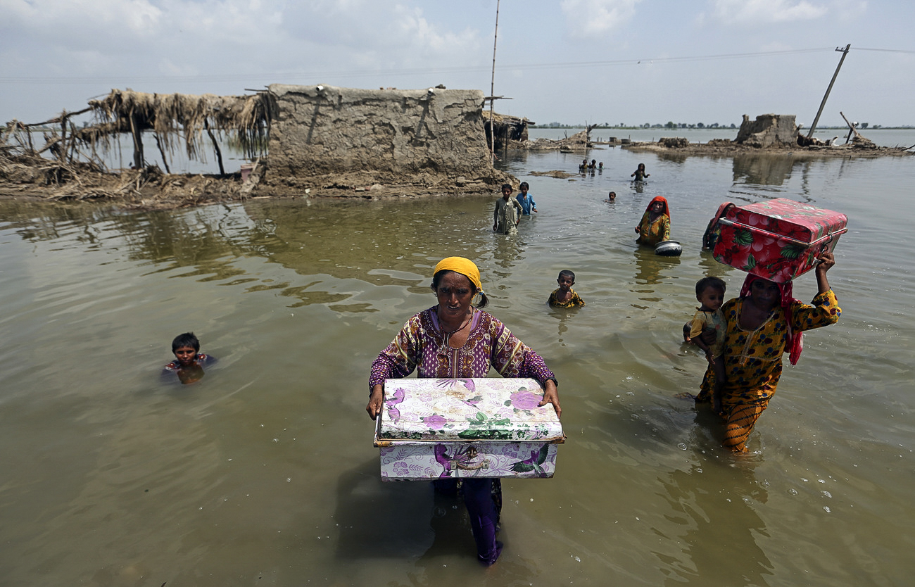 Des femmes transportent des biens récupérés dans leur maison inondée après les pluies de mousson, dans le district de Qambar Shahdadkot de la province de Sindh, au Pakistan, le 6 septembre 2022.