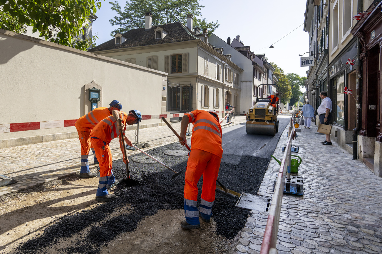 lavoratori asfaltano una strada