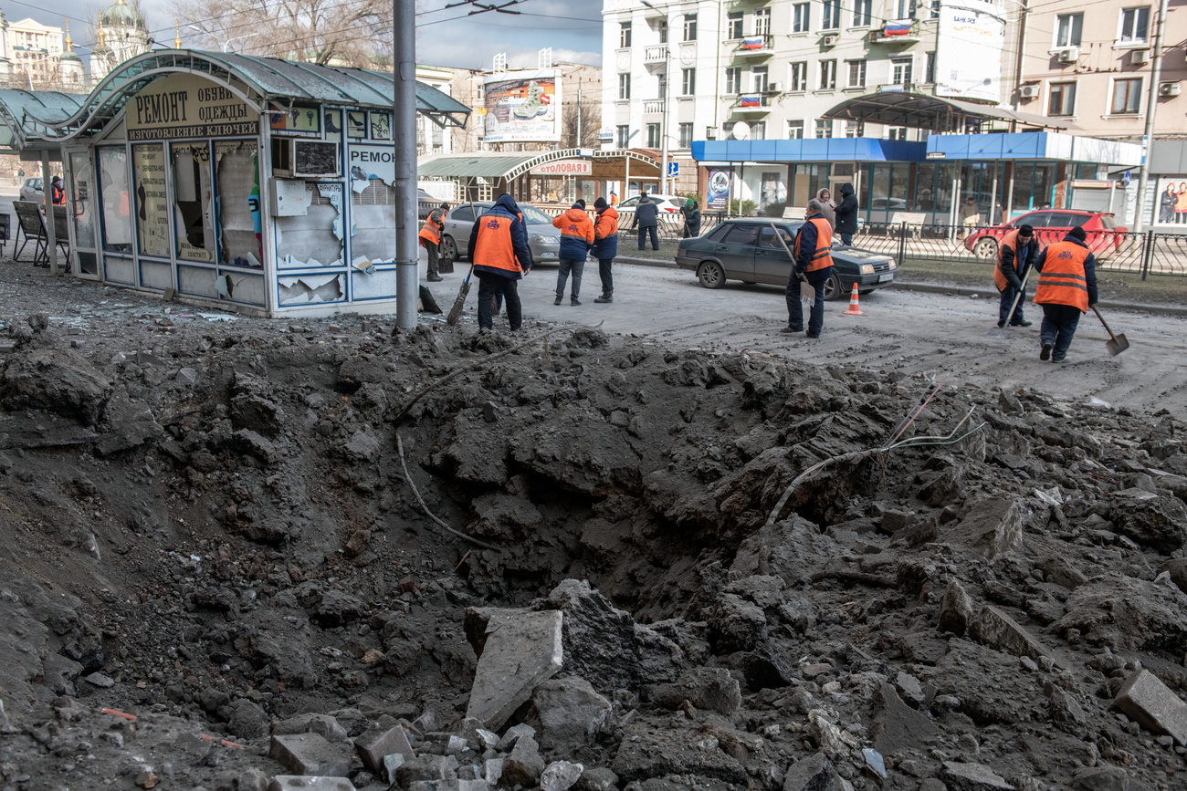 2024年2月20日，俄罗斯控制的乌克兰顿涅茨克市中心，市政工人在炮击后清理炮弹坑旁的街道。